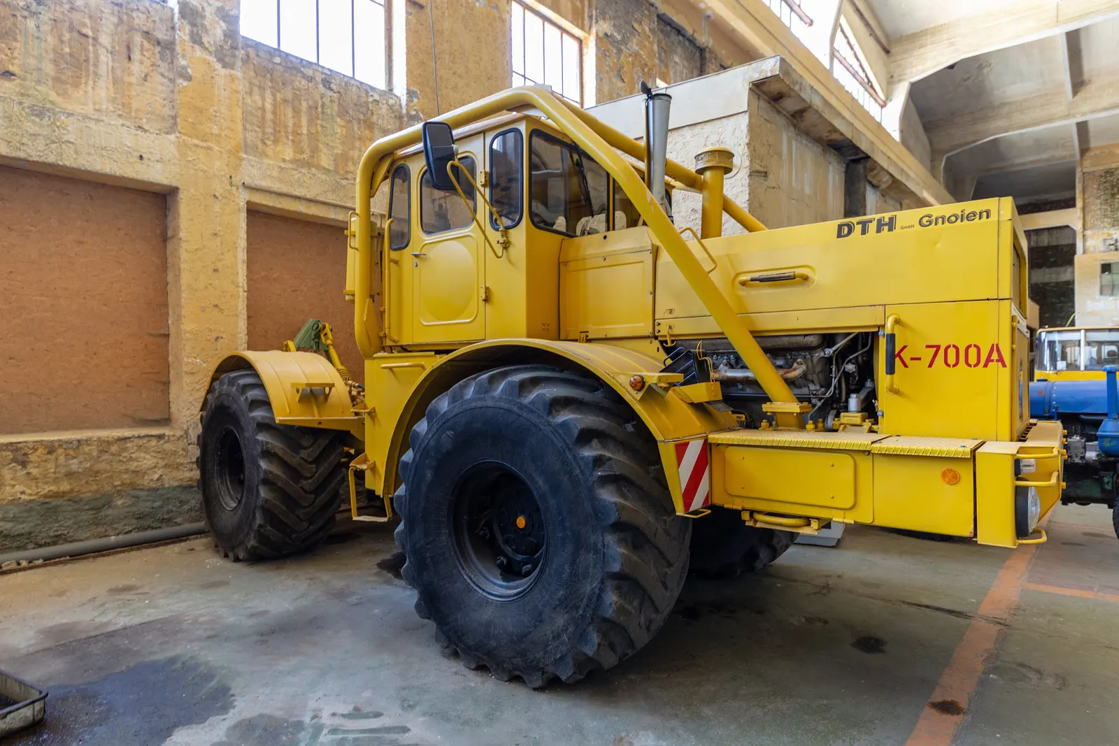 Žlutý K-700A s nápisem K-700A na kapotě v hale