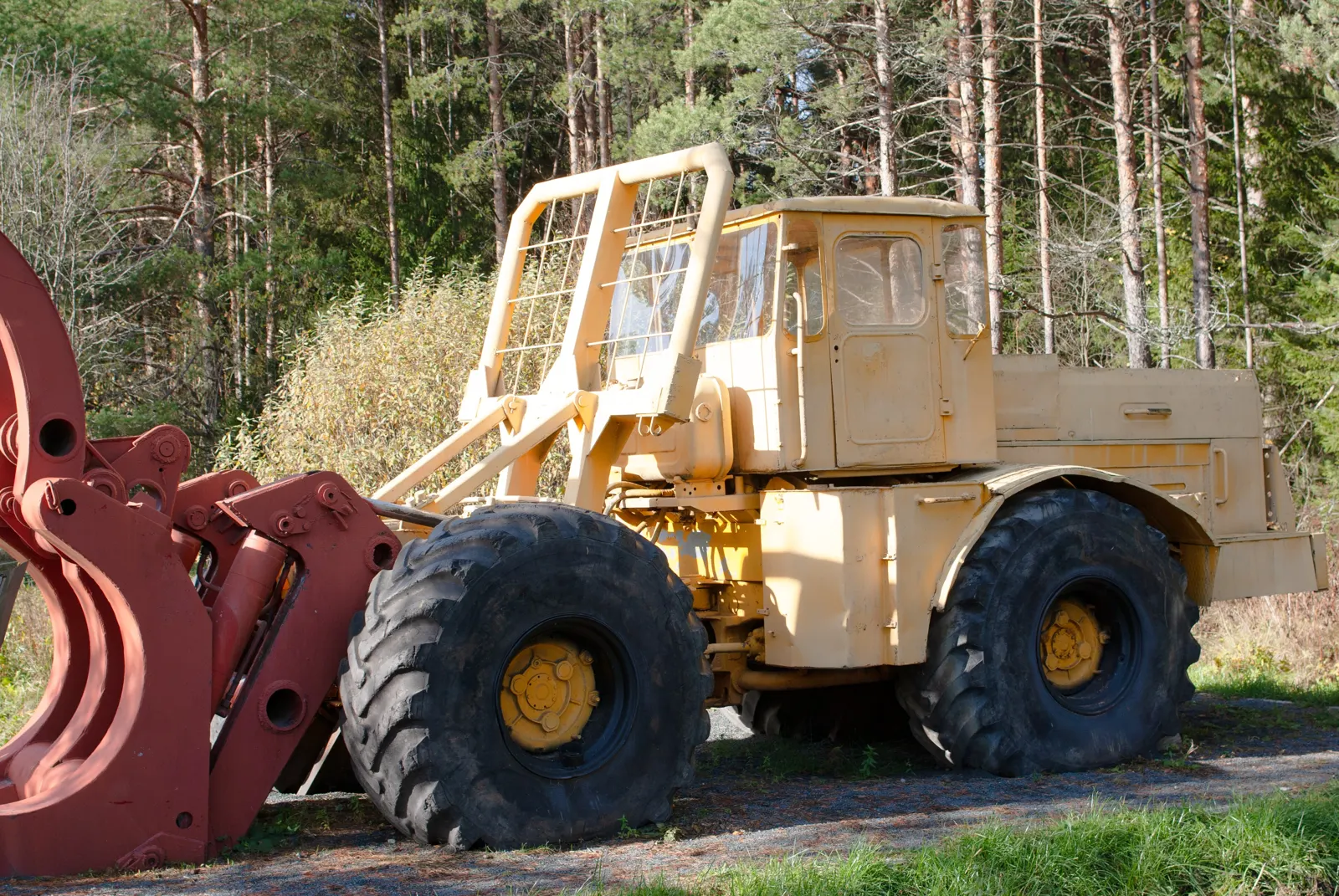 Béžový K-700A s čelním drapákem na kmeny