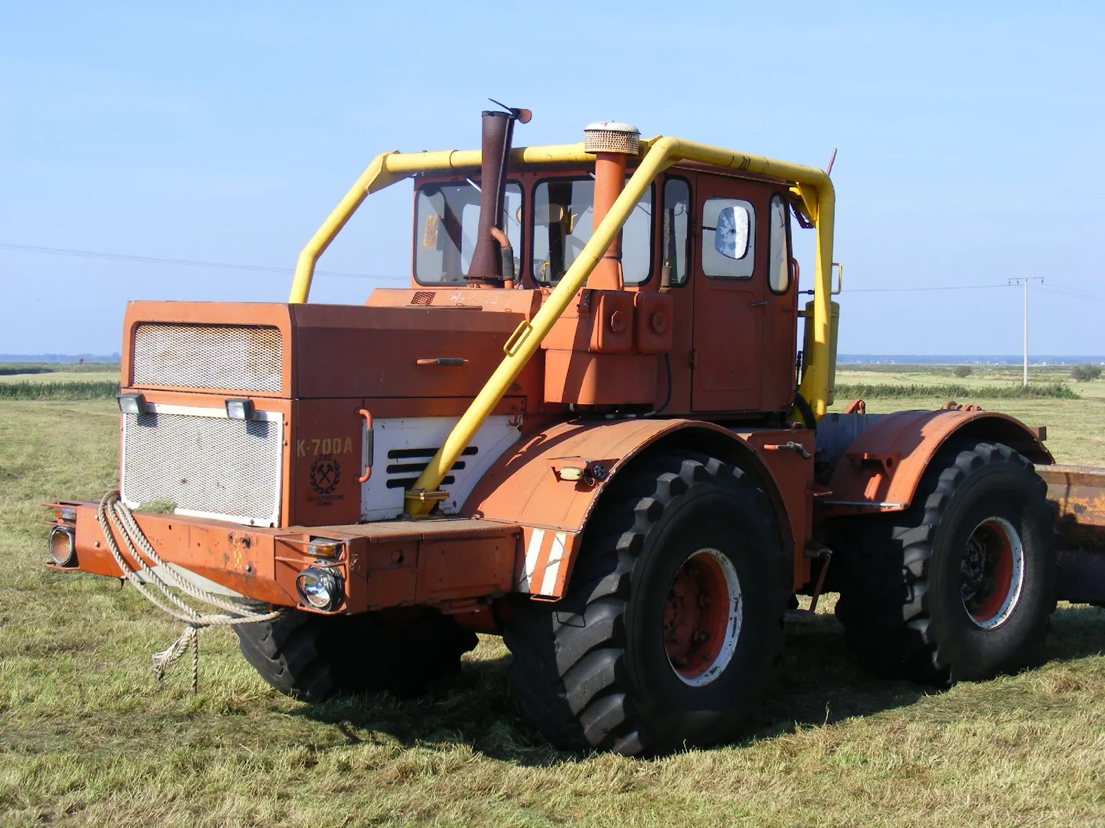 Oranžovožlutý K-700A stojí na louce