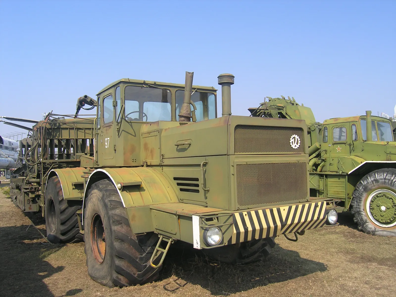 Olivově zelený K-701 táhne vojenský pokládač potrubí