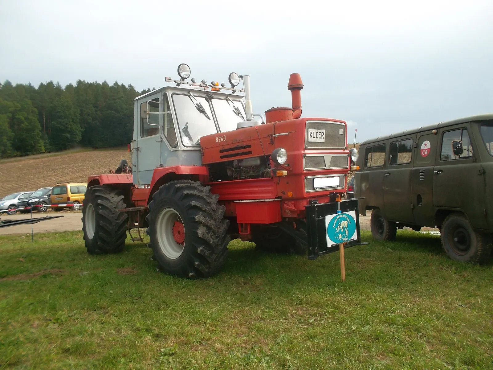 Červený traktor T-150K s bílou kabinou na louce