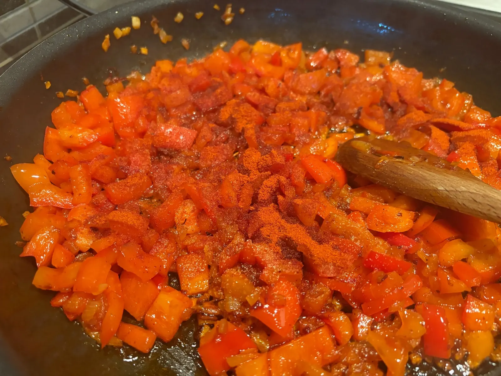 Mletá paprika nasypaná na cibuli s kapií v pánvi