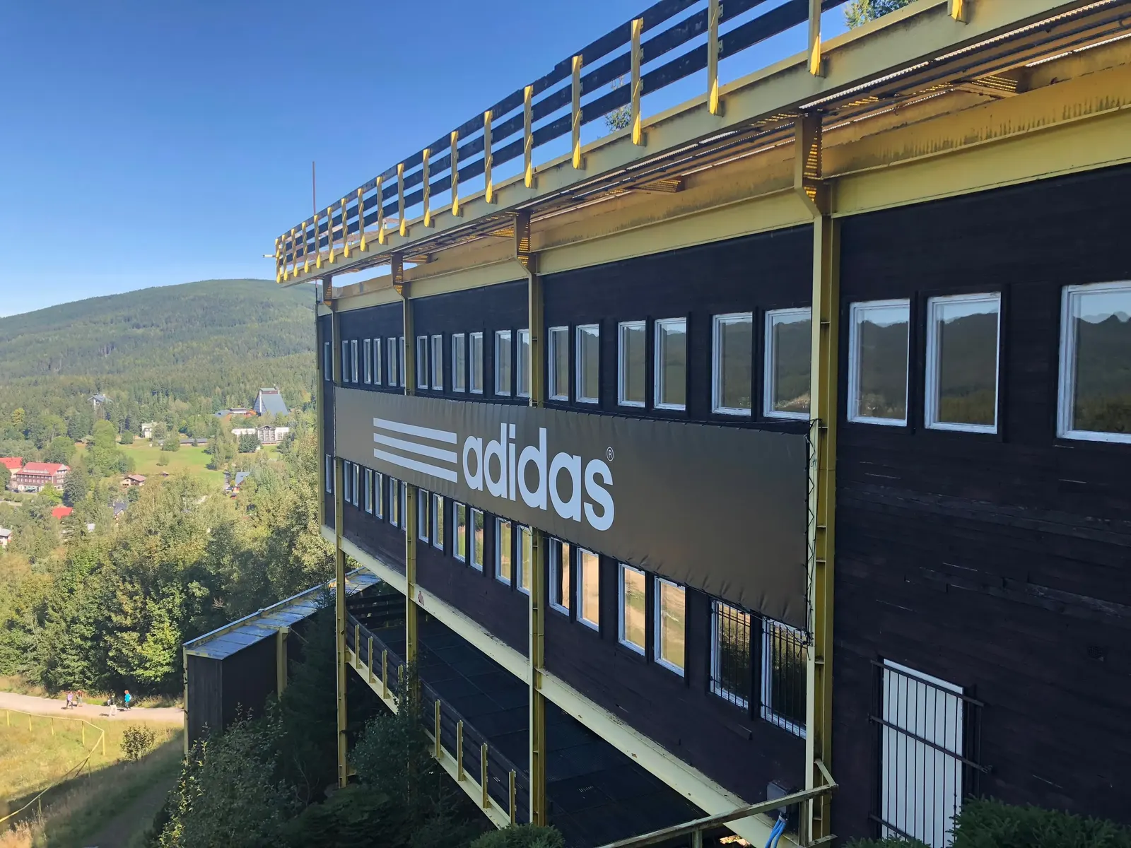 Dřevěná budova s řadami oken u doskočiště s plachtou adidas