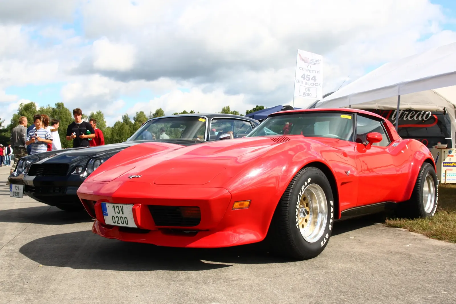 Červená Chevrolet Corvette C3 vedle černého Trans Amu s cedulí 454 Big Block