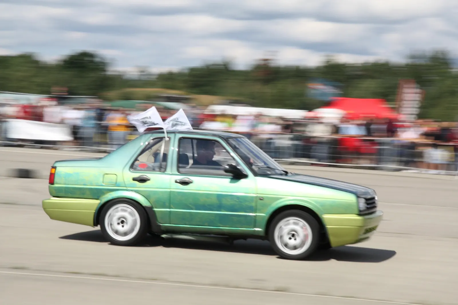 Zelený Volkswagen Jetta v rozostřeném pohybu na sprintové dráze