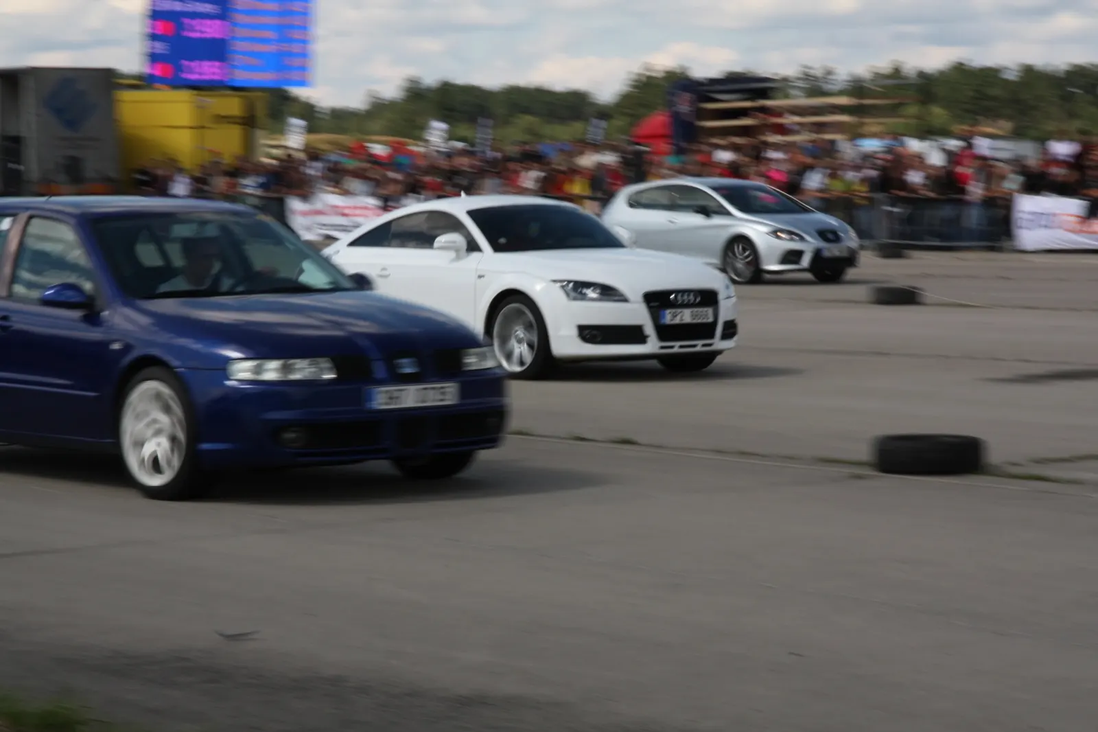 Tři auta - modrý Seat, bílé Audi TT, stříbrný Seat - v pohybu po startu