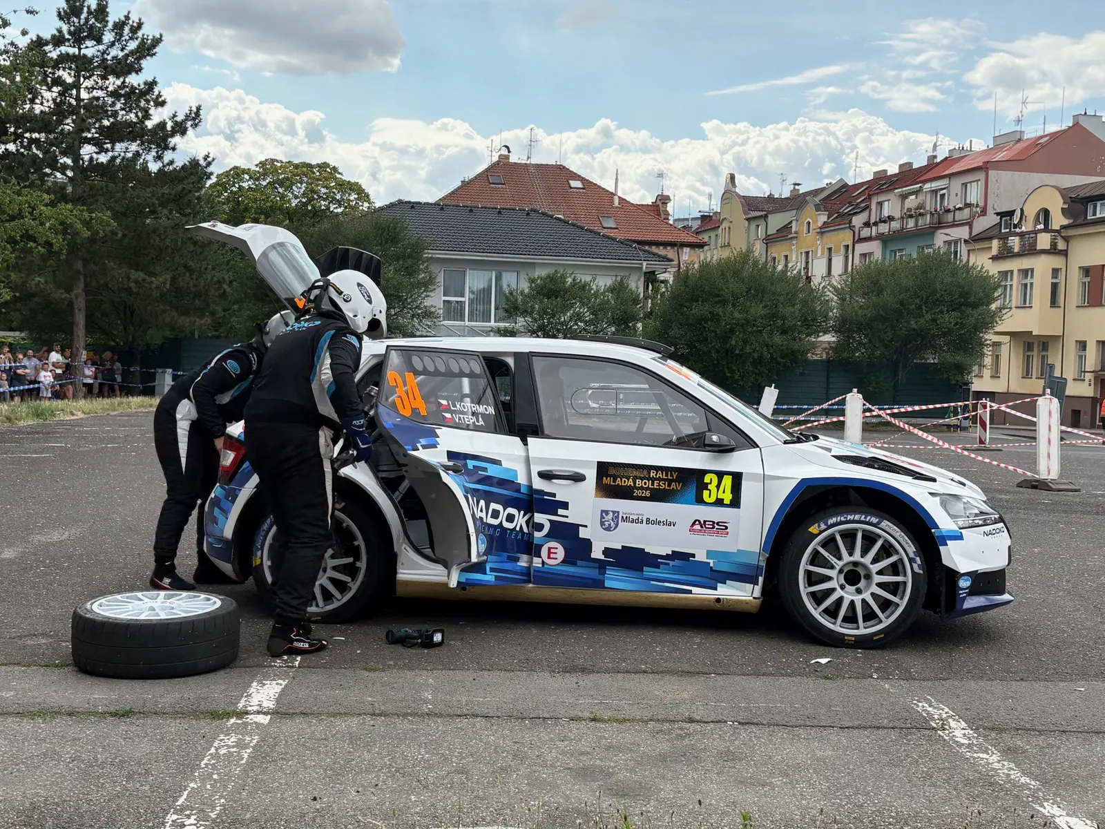 Posádka Kotrmon / Teplá mění kolo přímo v servisní zóně Rally Bohemia 2026, rezerva opřená vedle vozu