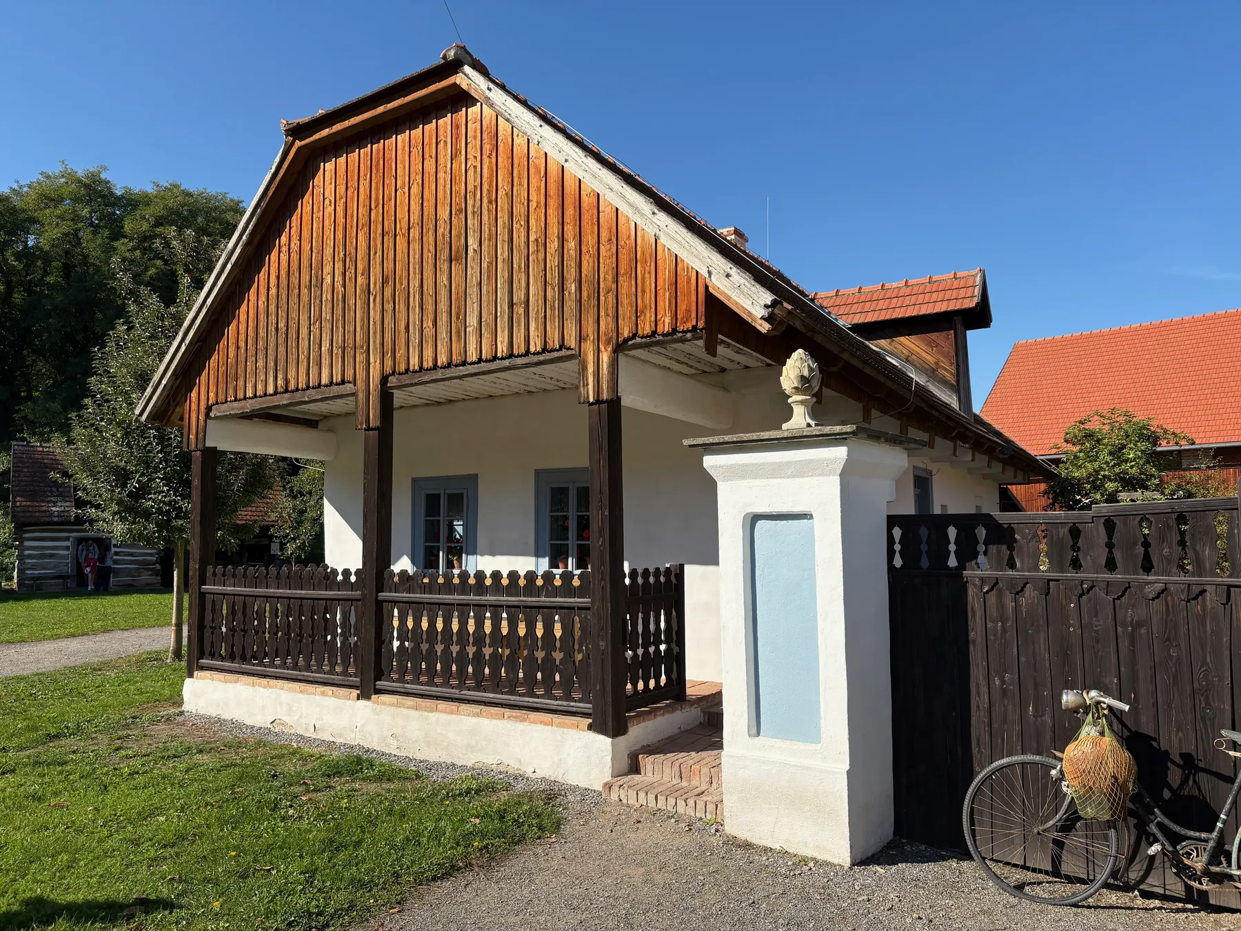 Boční pohled na malou žlutou stavbu s dřevěným vstupem