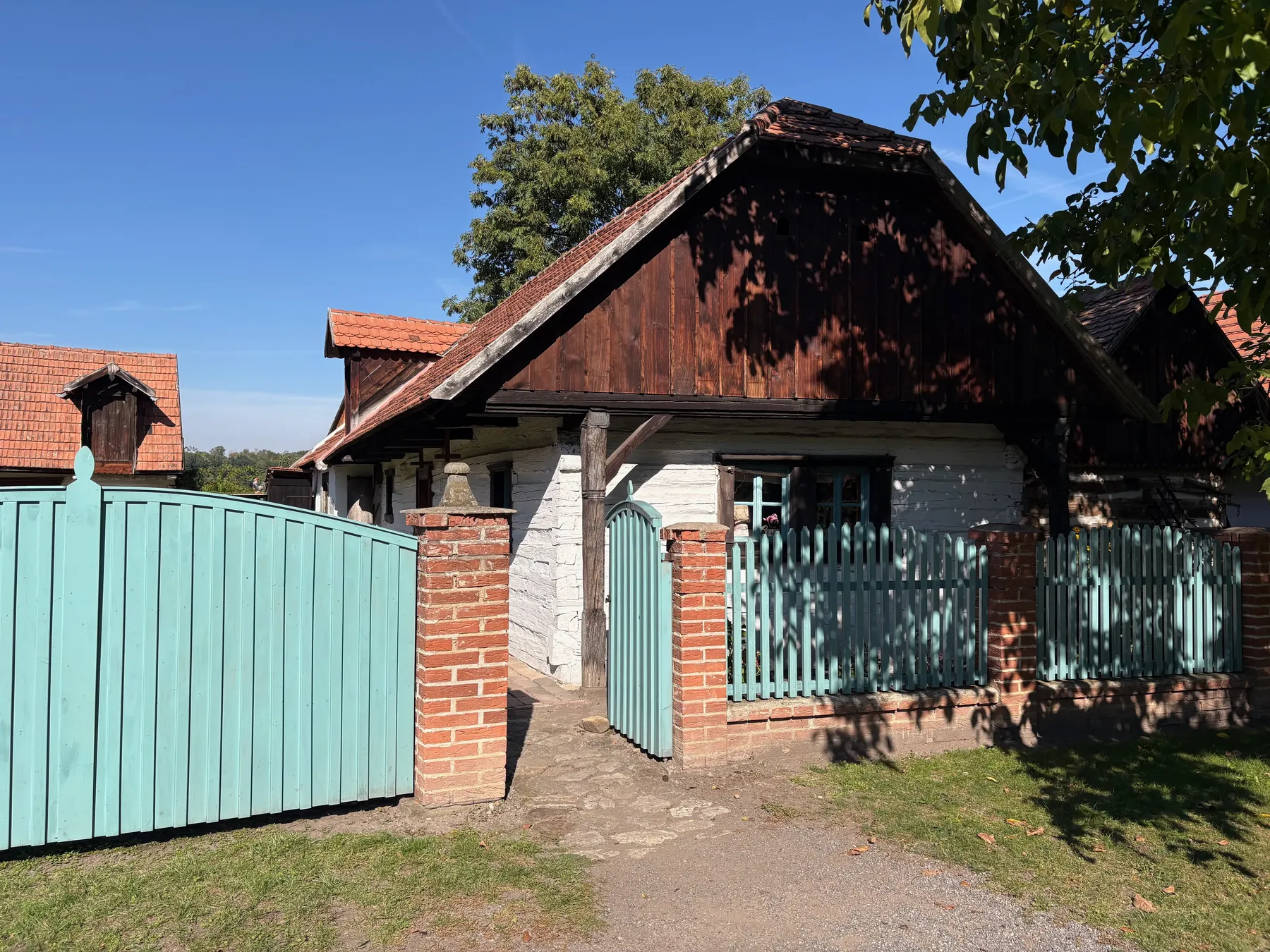 Tyrkusově modrá vrata z prken a laťový plot před chalupou z Pojed