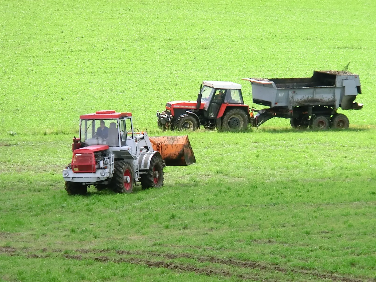 ŠT 180 N s nakladačem na poli, v pozadí Zetor s rozmetadlem
