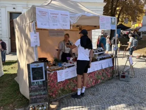 Vinný stánek s cenami palačinek a koláčů, obsluha za pultem
