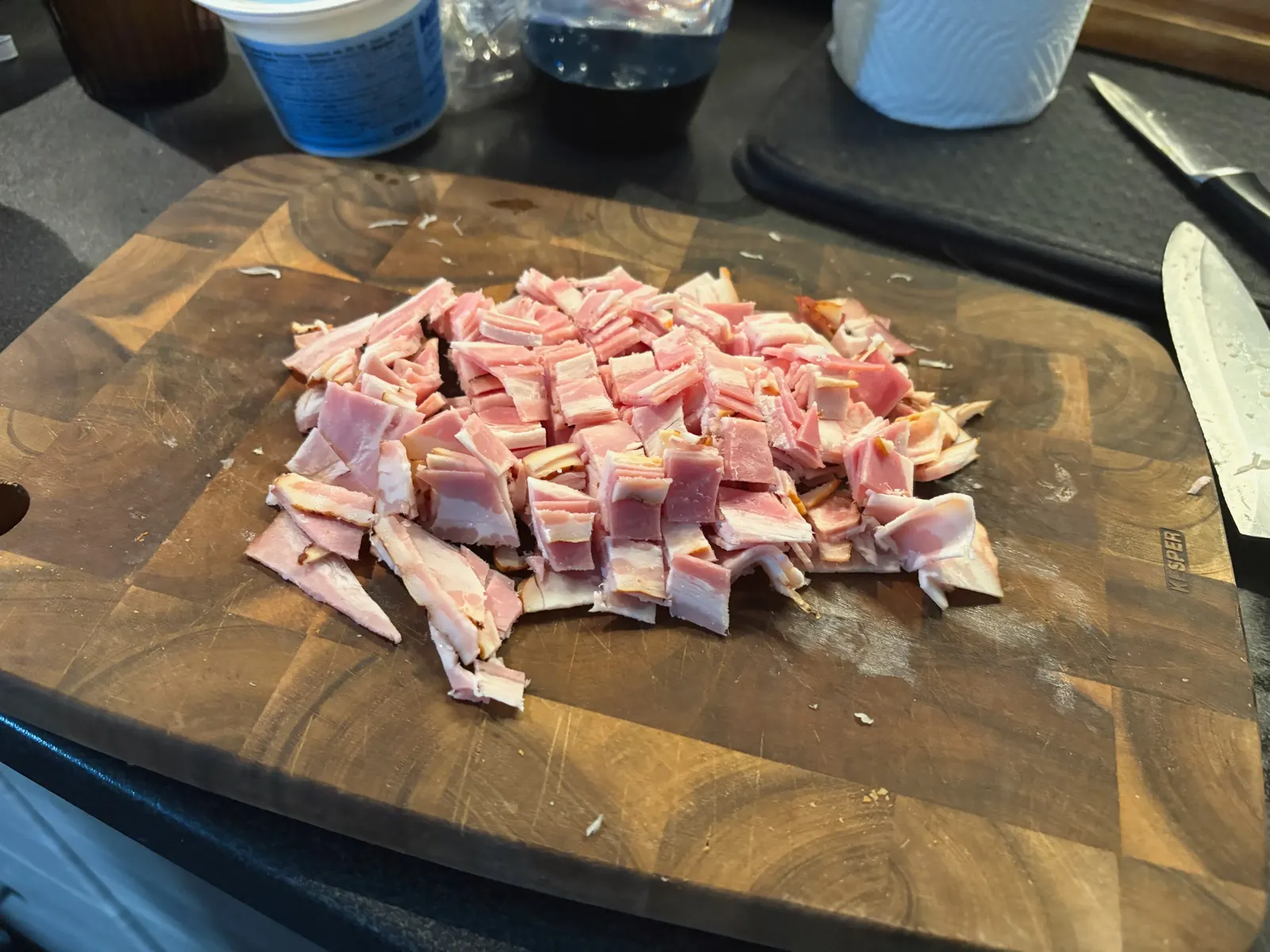 Syrová slanina nakrájená na kousky na dřevěném prkénku
