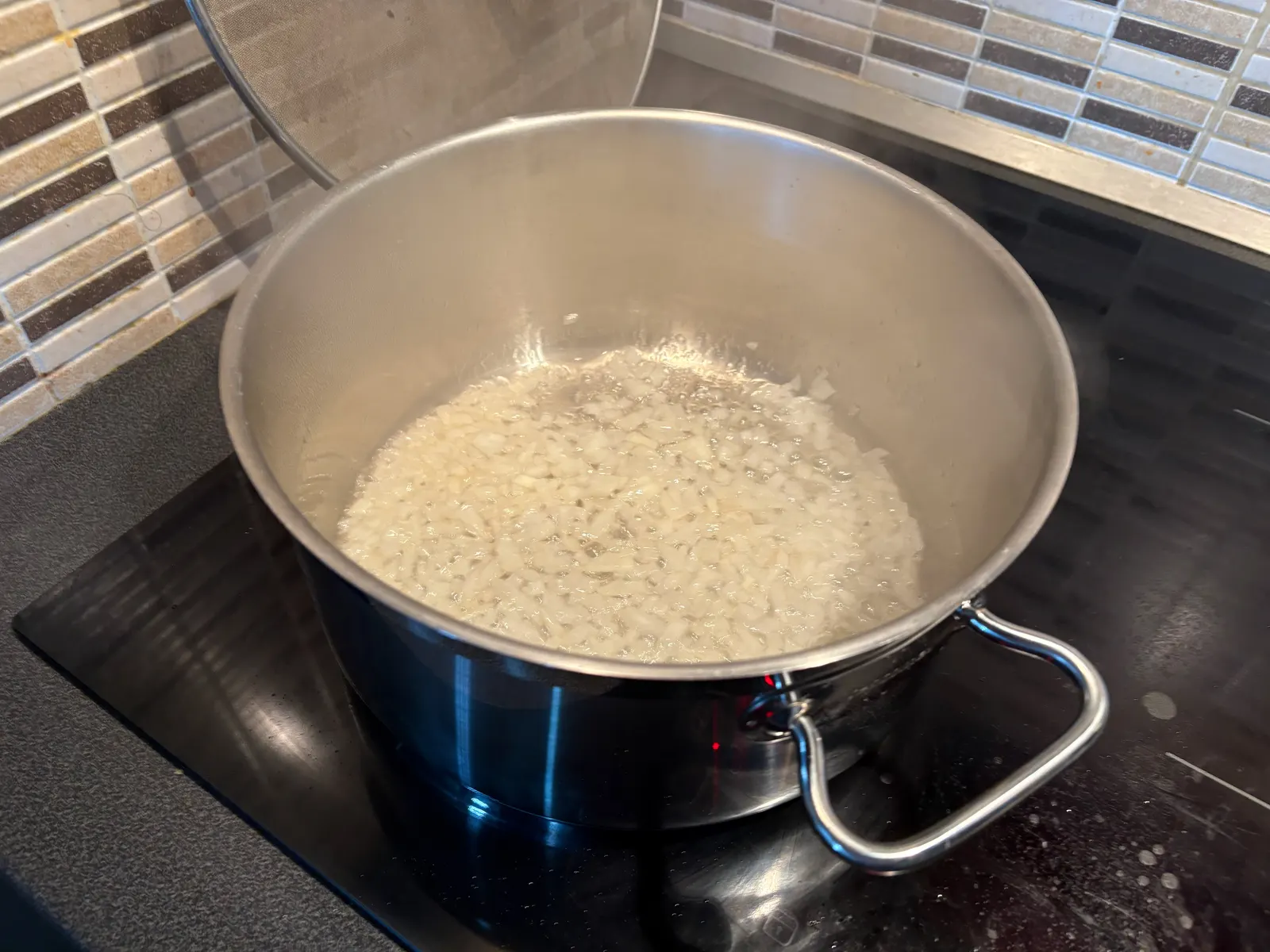 Cibule v rozpuštěném sádle na plotně, začíná průsvitnět